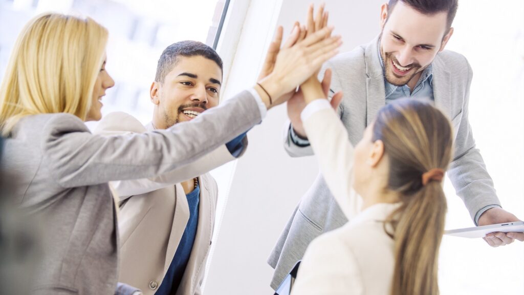 Shot of a group of colleagues high-fiving each other during an informal meeting.Happy business team celebrating good news.